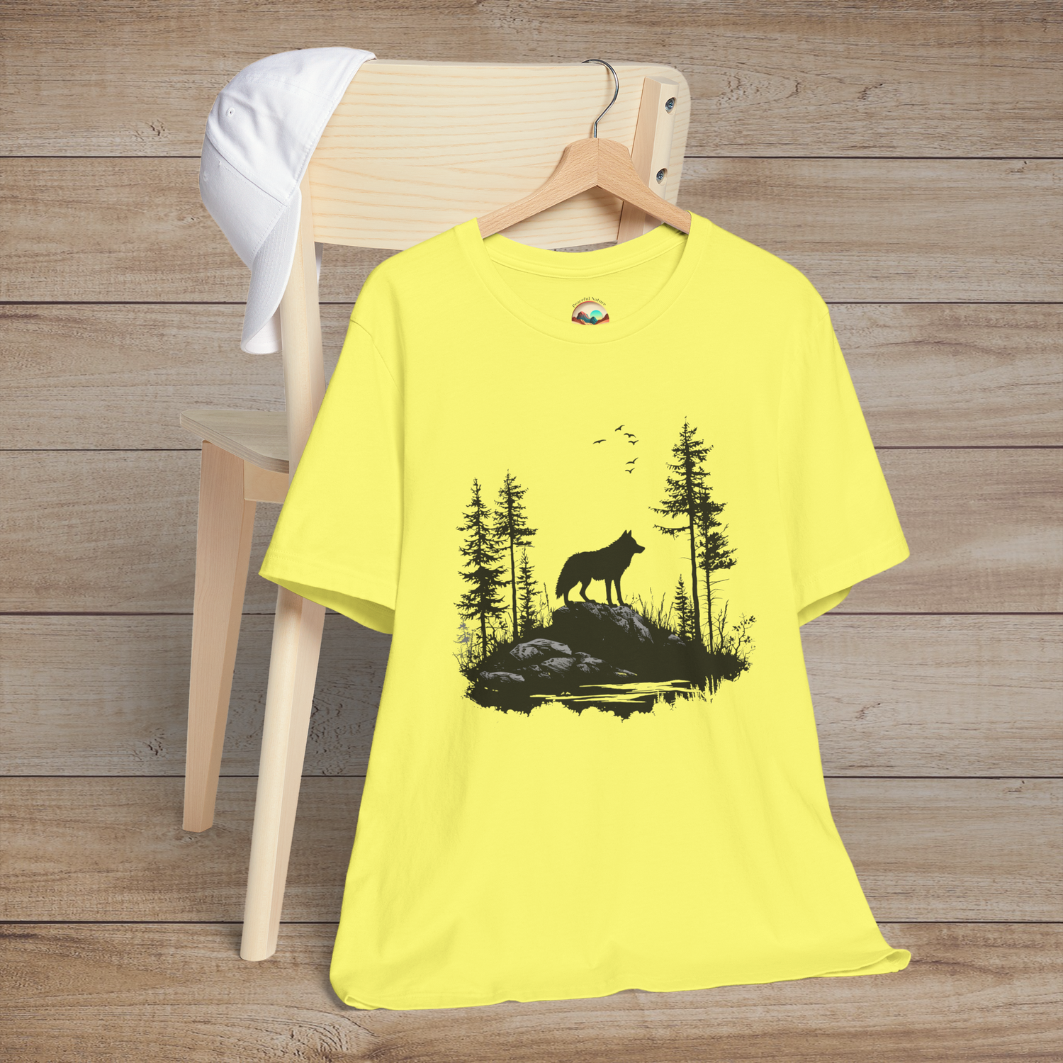 Bright yellow t-shirt with a black silhouette of a lone wolf standing on rocks amid a tranquil forest, birds flying overhead for a bold nature vibe