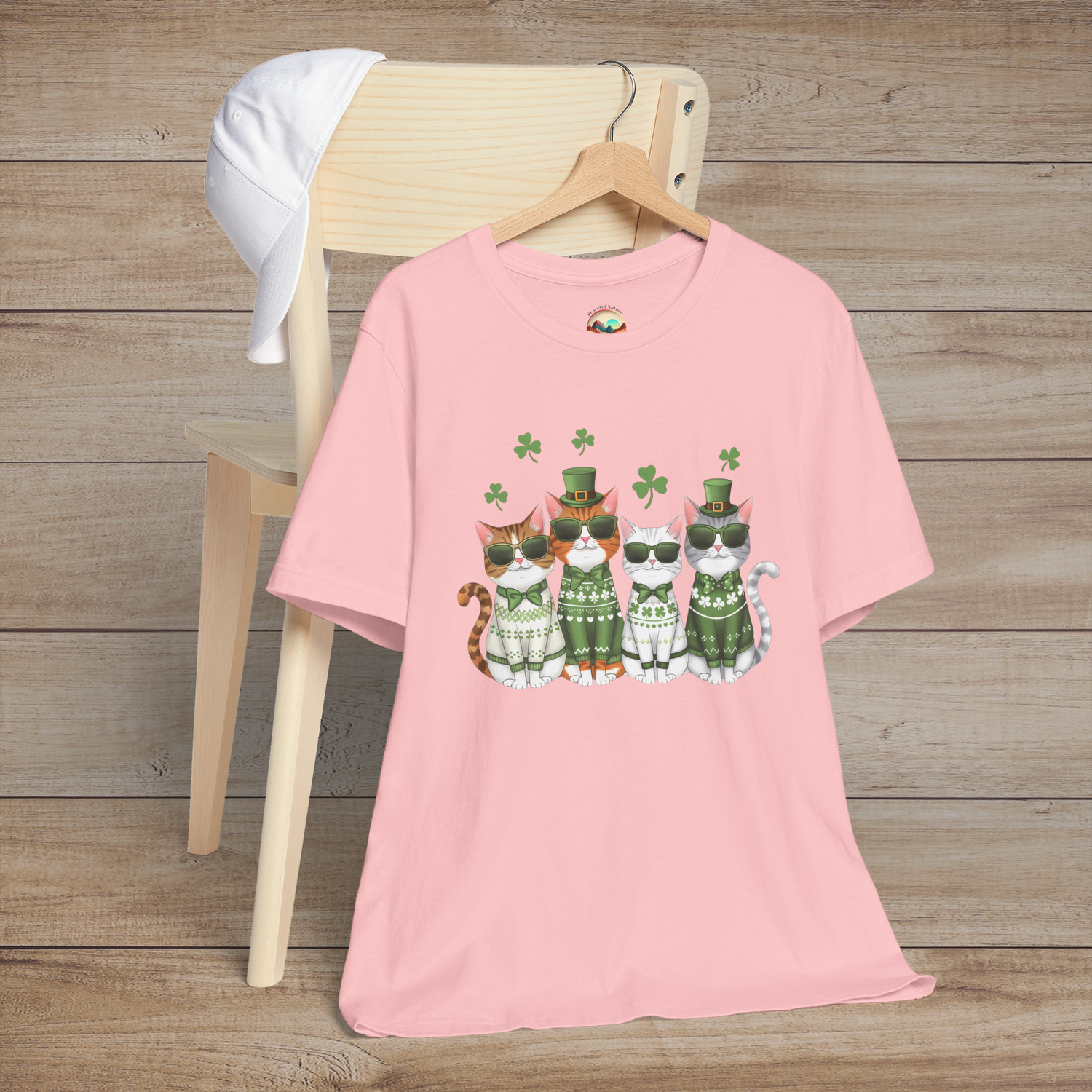 Pink t-shirt displaying festive St. Patrick’s Day cats wearing green outfits, sunglasses, and surrounded by shamrocks