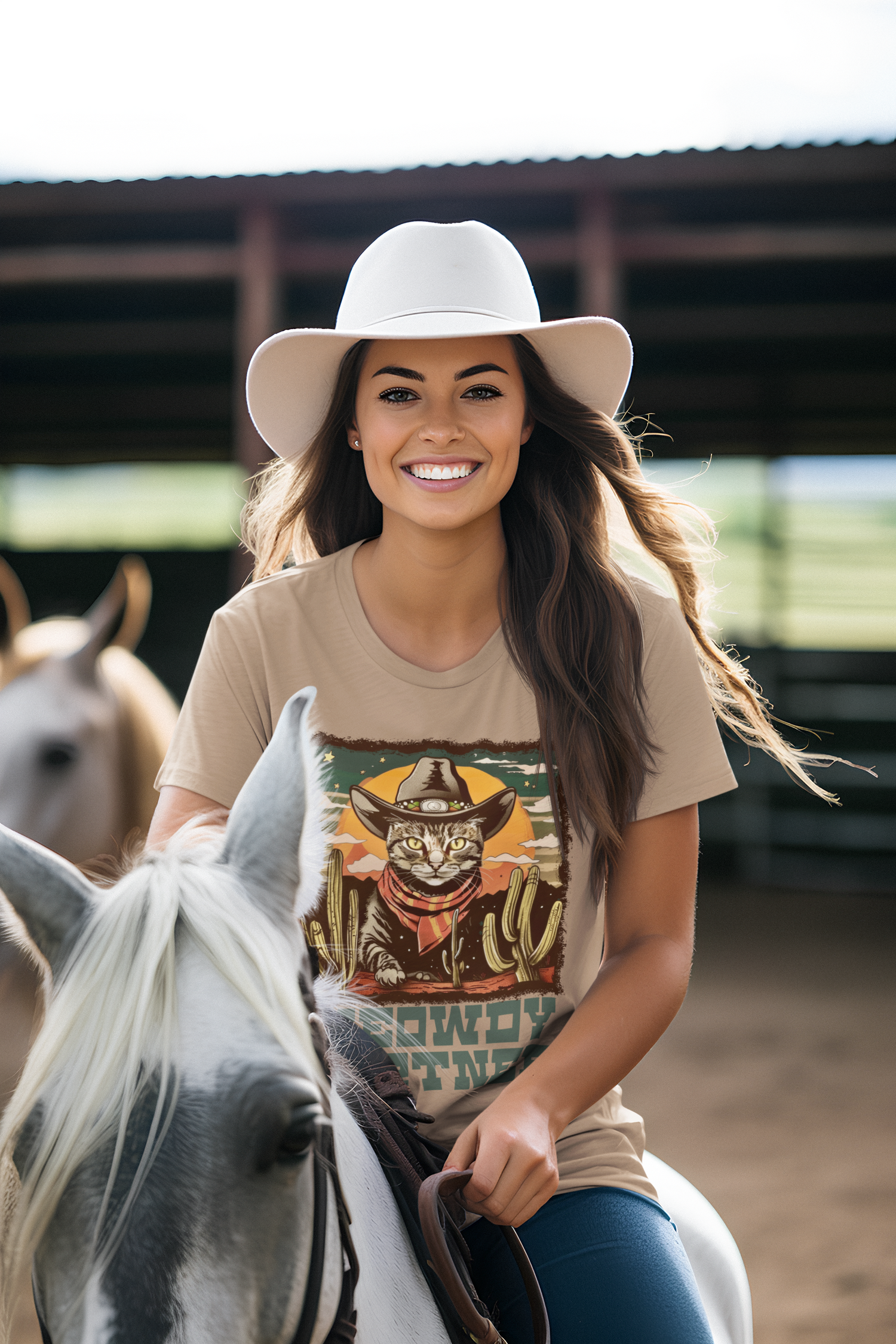 Joyful female model riding a horse in the Heather Tan Meowdy Partner Cowboy Cat T-Shirt, Western cat graphic tee