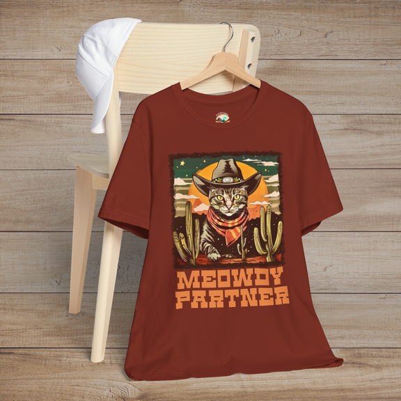 Rust Meowdy Partner Cowboy Cat Western Tee showing a whimsical cat dressed in cowboy attire, complete with hat and neckerchief against a desert and cactus background.