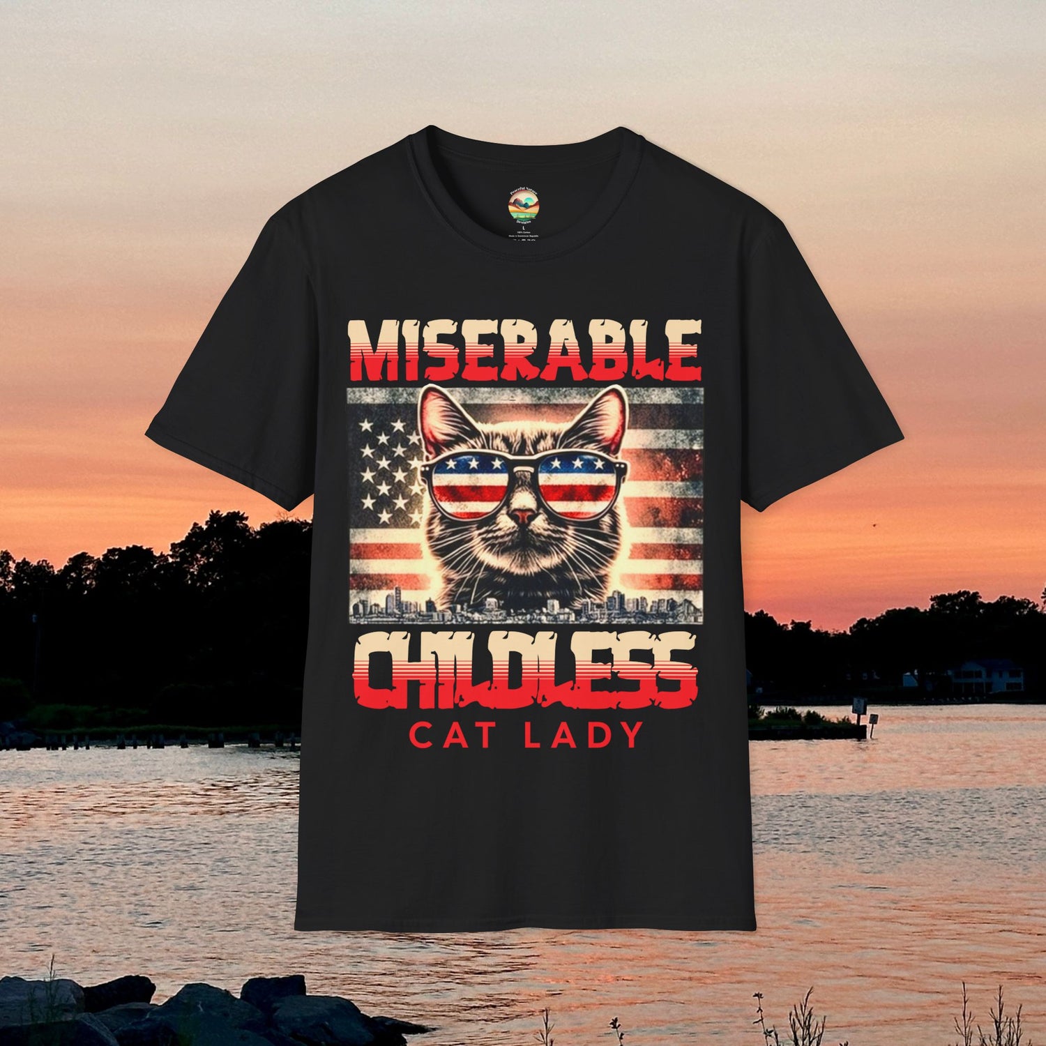 Flat lay of the "Miserable Childless Cat Lady" soft fit t-shirt in black, displayed against a sunset background