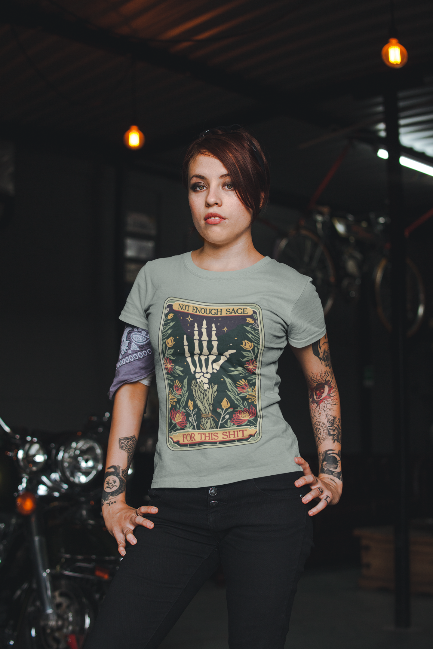 Stylish female model in Sage Green Not Enough Sage for This Sh*t Tee, posing confidently with goth-boho vibes in a motorcycle-themed setting