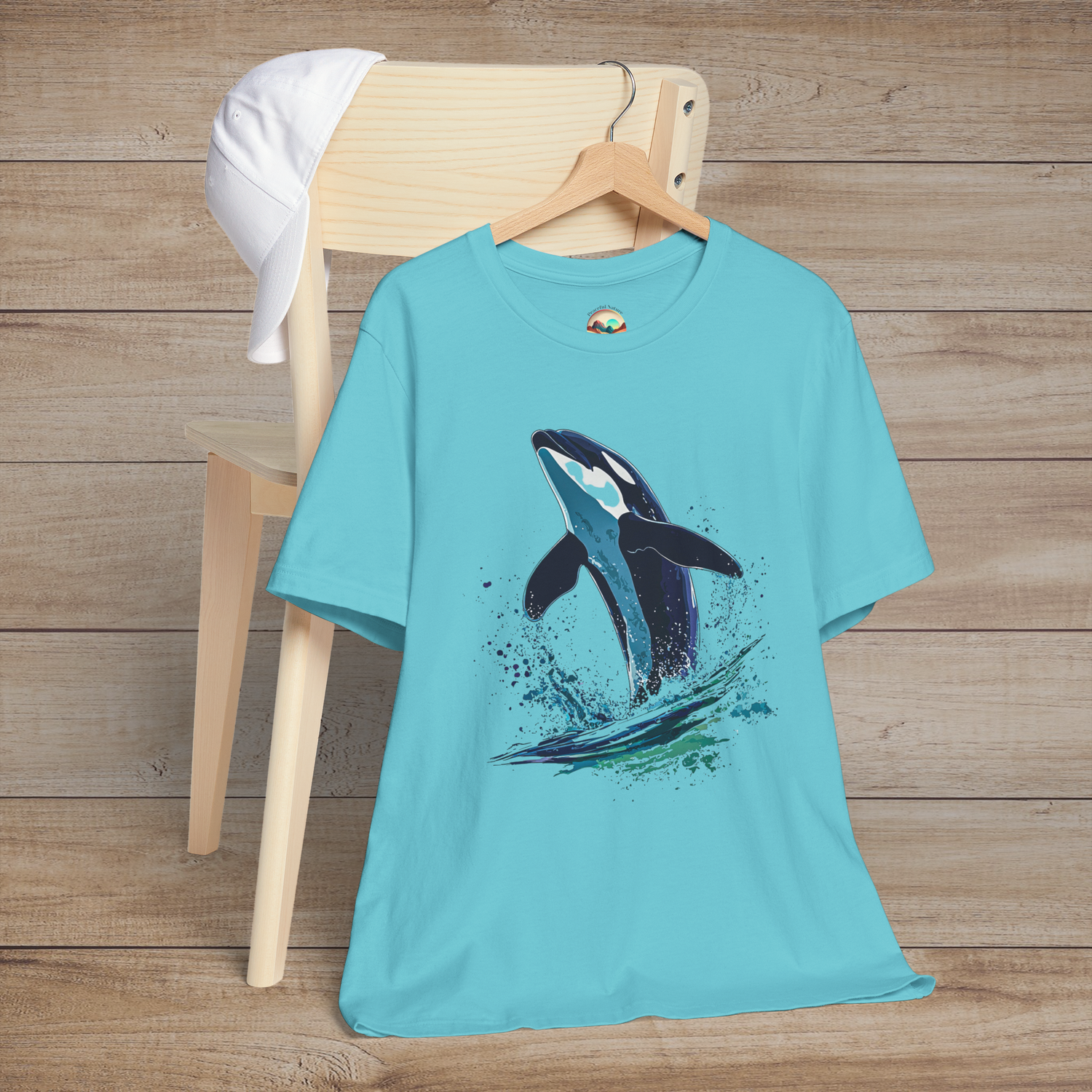 Turquoise Bella+Canvas tee with orca whale mid-leap in marine spray