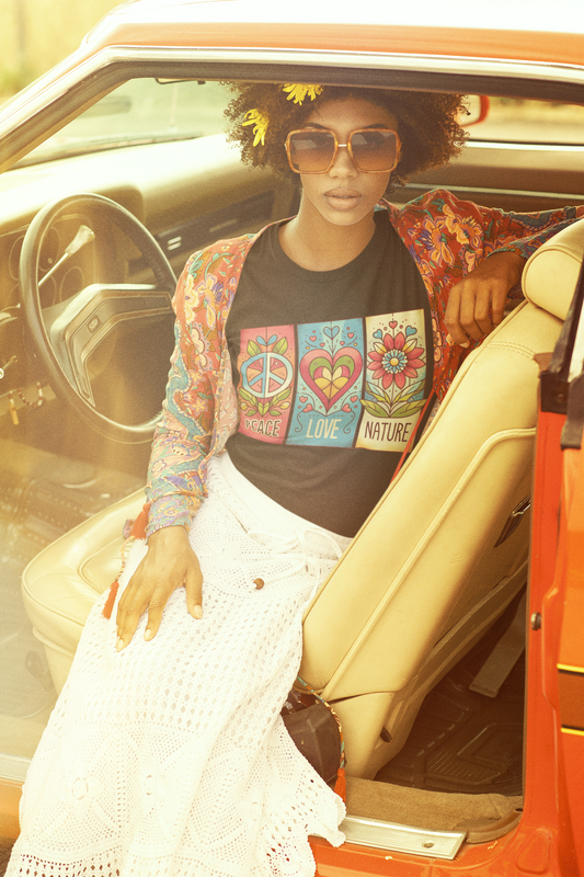 Female model sitting in a vintage car wearing black Peace Love Nature t-shirt, accessorized with oversized sunglasses and a floral cardigan