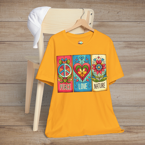 Gold variant of the Peace Love and Nature T-Shirt laid on a chair with white hat, featuring a bold design of peace sign, heart, and flower blocks in vivid reds, blues, and greens. A statement piece for outdoor and festival wear