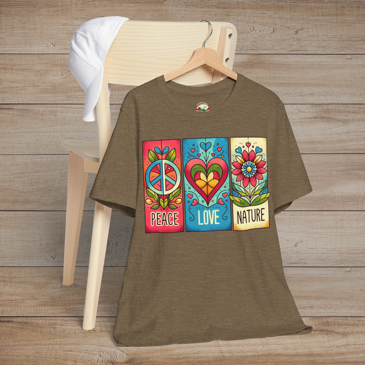 Heather olive Peace Love and Nature T-Shirt hung on a wood chair, featuring a retro graphic print with floral elements and symbolic icons in earthy red and gold tones. A must-have tee for lovers of peace and nature