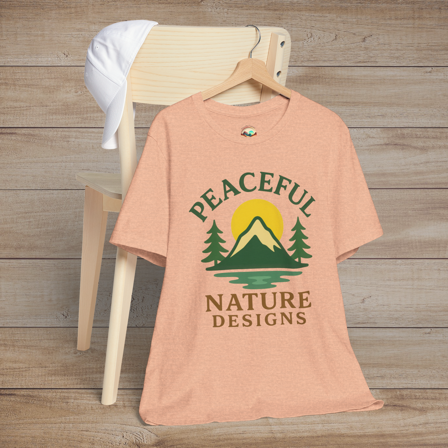 Peaceful Nature Designs premium t-shirt in heather peach featuring a mountain, trees, and sun graphic