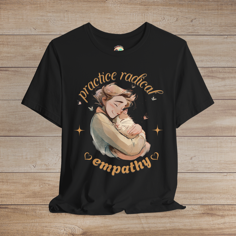 Black tee with a heartwarming illustrated design of a person hugging a cat, surrounded by butterflies and stars, captioned “Practice Radical Empathy.”
