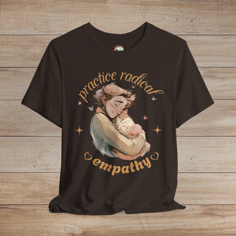 Brown tee featuring a loving illustration of a person embracing a content cat, with soft butterfly accents and warm text reading “Practice Radical Empathy.”