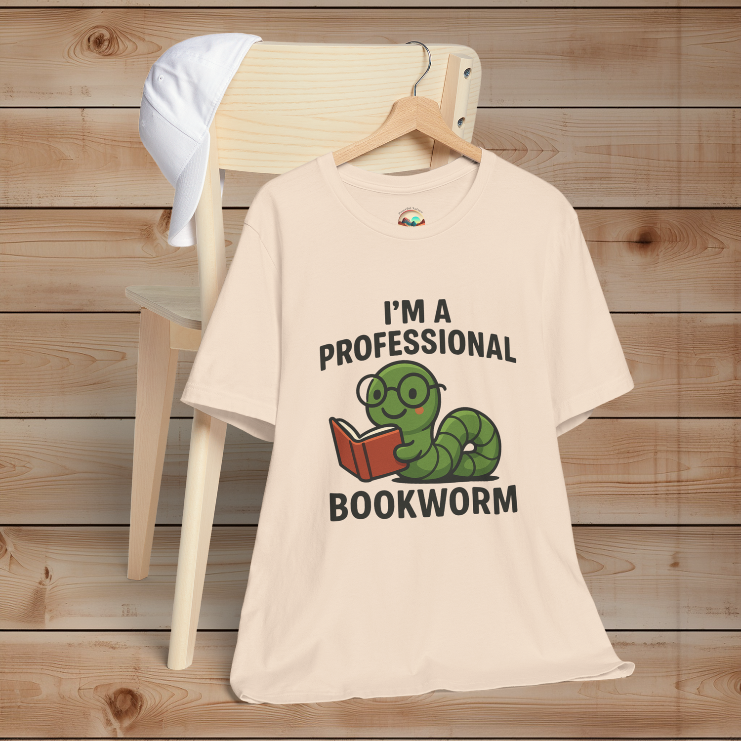 Soft cream t-shirt with a graphic and text 'I'm a Professional Bookworm' on a wooden background