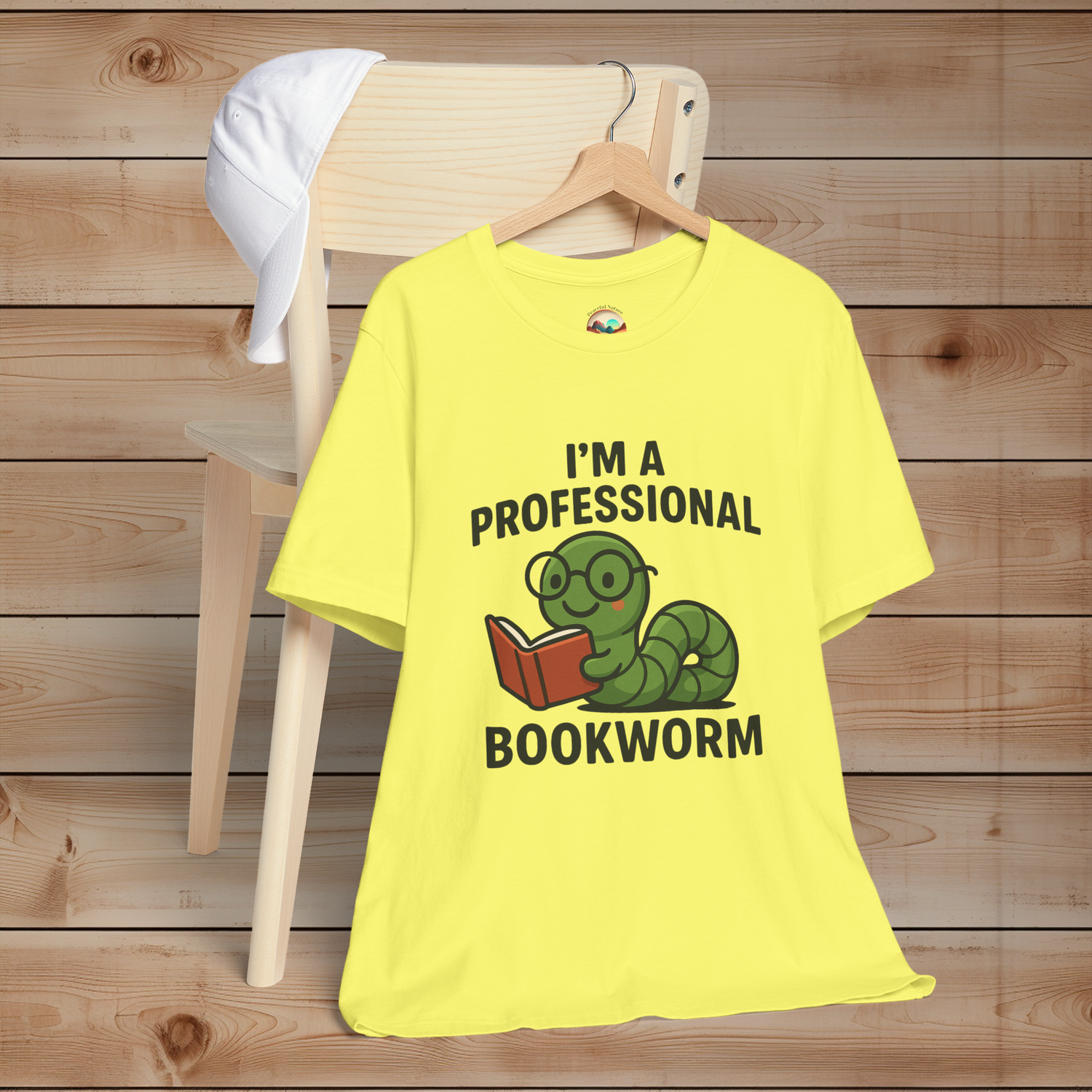 Yellow t-shirt with a bookworm graphic and text on a wooden background