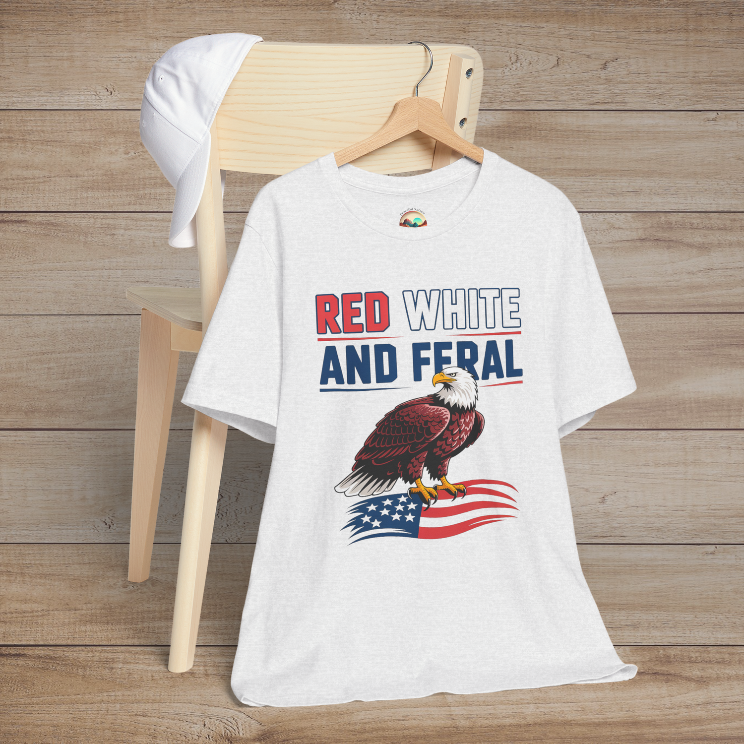 Patriotic eagle t-shirt in ash gray featuring the phrase "Red White and Feral" with a bold eagle perched on a waving American flag.