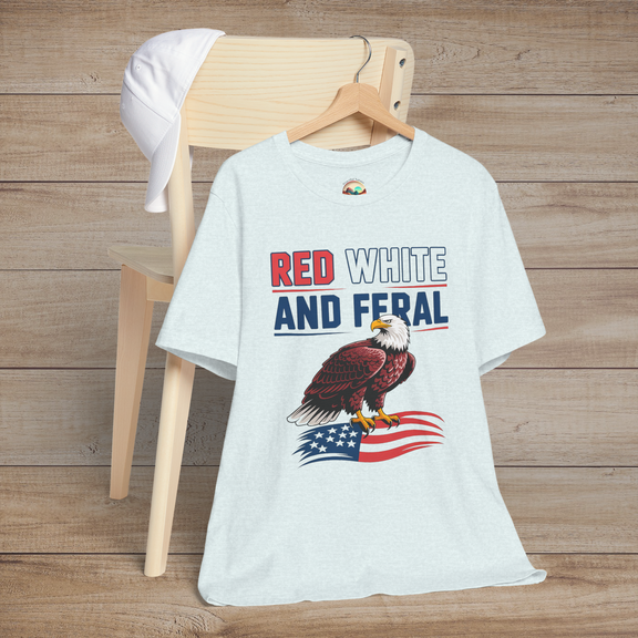 Fourth of July-themed graphic tee in heather ice blue with a fierce bald eagle and the text "Red White and Feral" in bold patriotic colors.