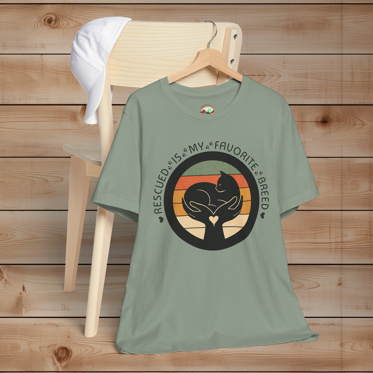 Sage green Bella+Canvas 3001 unisex tee – minimalist cat and hands graphic with vintage stripes, ‘Rescued Is My Favorite Breed’ text.