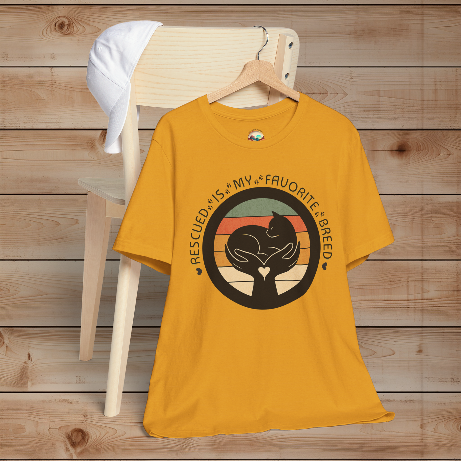 Mustard yellow ‘Rescued Is My Favorite Breed’ animal rescue shirt – cat silhouette in hands, heart-centered retro artwork.