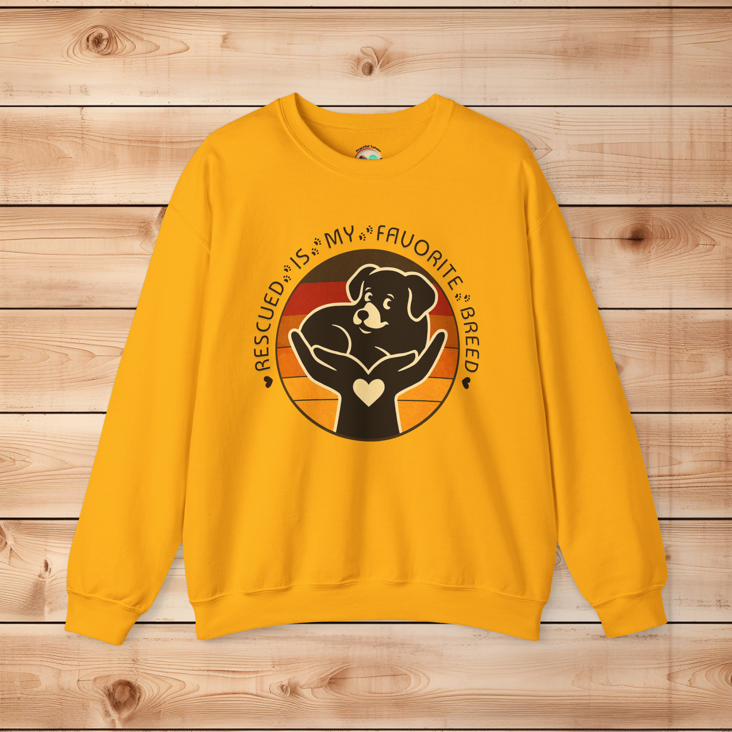 Gold Gildan 18000 sweatshirt with Rescued Is My Favorite Breed dog rescue design showing a puppy in caring hands against a warm vintage sunset.