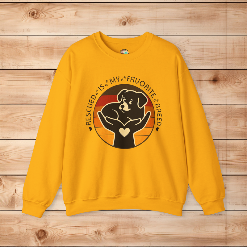 Gold Gildan 18000 sweatshirt with Rescued Is My Favorite Breed dog rescue design showing a puppy in caring hands against a warm vintage sunset.