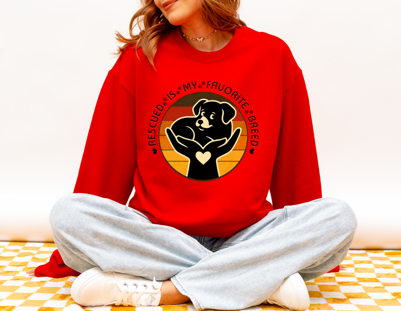 Model wearing bright red Gildan 18000 Rescued Is My Favorite Breed sweatshirt with vintage sunset dog rescue artwork.