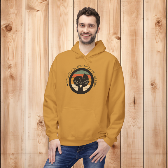 Male model wearing a mustard-colored 'Rescued Is My Favorite Breed' retro cat rescue hoodie in front of a wooden panel background.