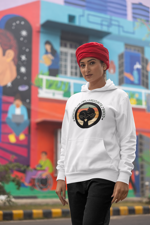 Woman wearing a white 'Rescued Is My Favorite Breed' retro cat rescue hoodie and a red turban while posing on a city street