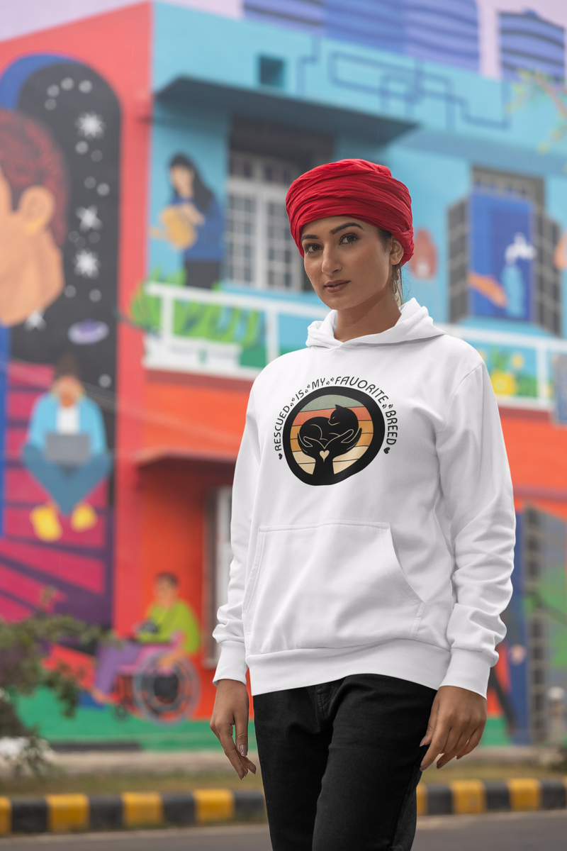 Woman wearing a white 'Rescued Is My Favorite Breed' retro cat rescue hoodie and a red turban while posing on a city street