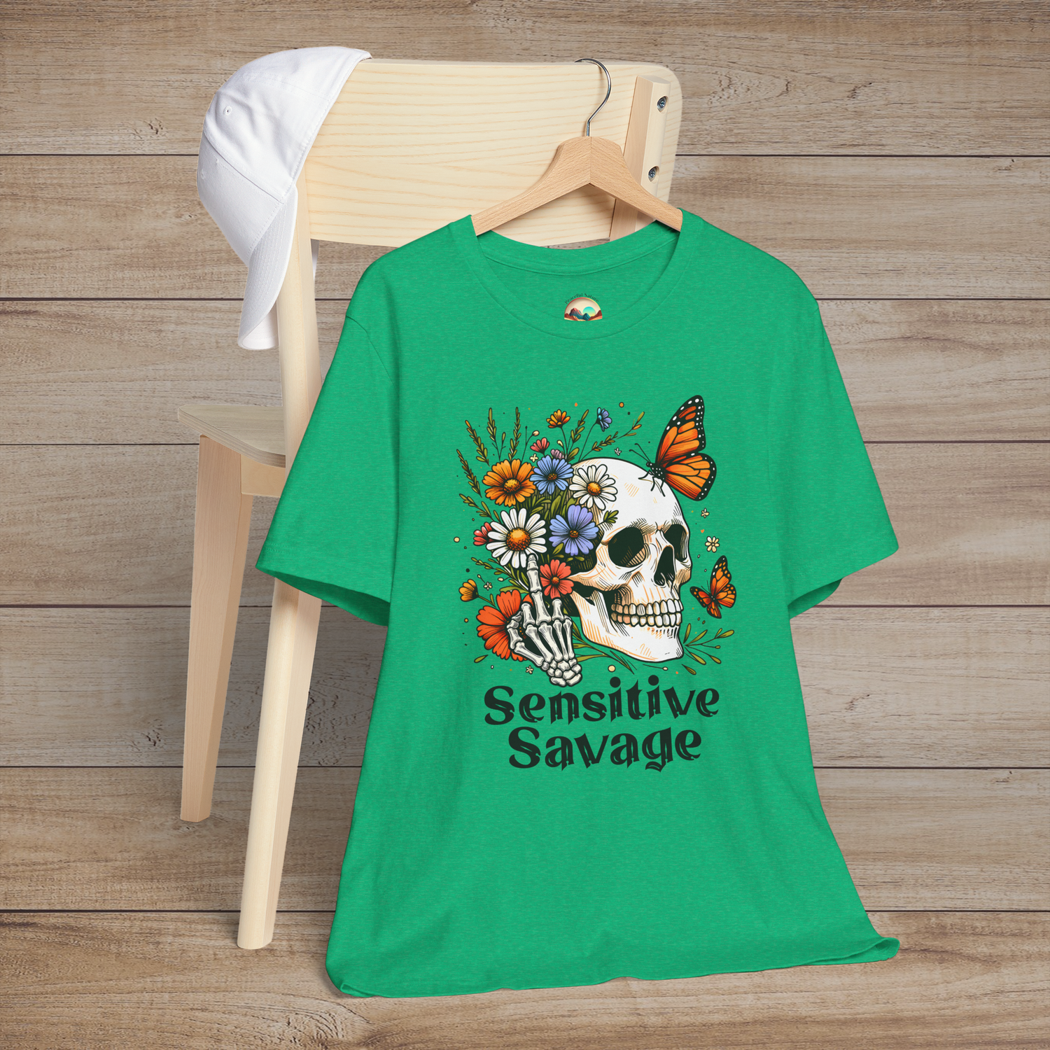 Heather kelly green t-shirt with a boho-gothic style skull, colorful flowers, orange butterflies, and Sensitive Savage text