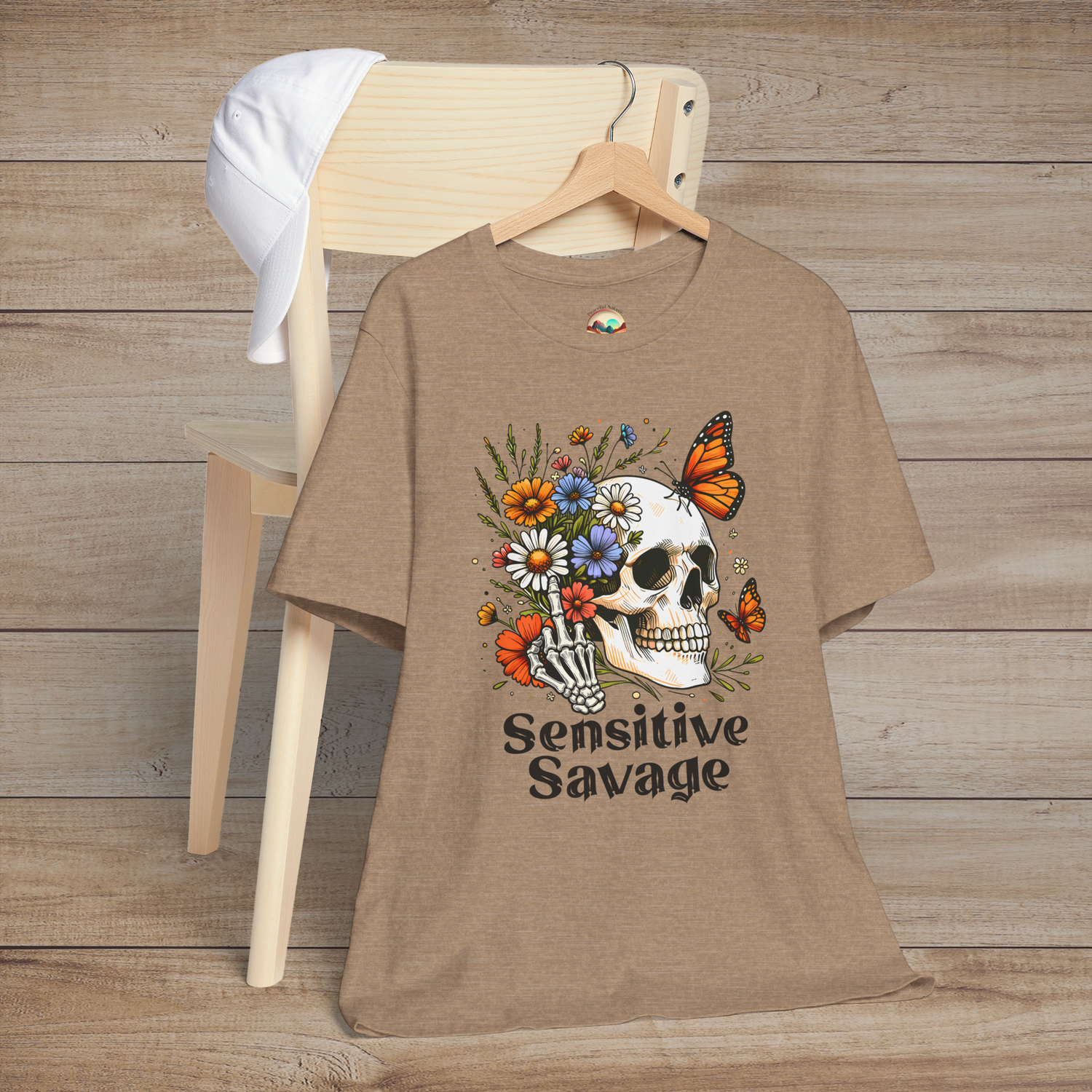 Heather tan t-shirt with boho-goth design of a floral-decorated skull, butterflies, and Sensitive Savage text below