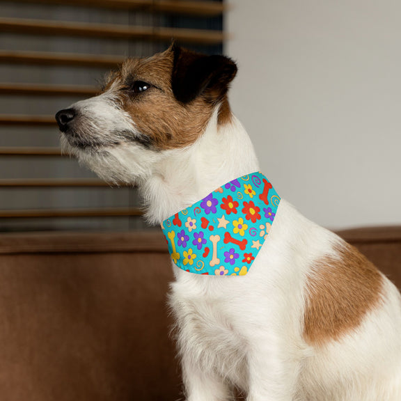 Small dog sitting indoors wearing a bright, printed bandana