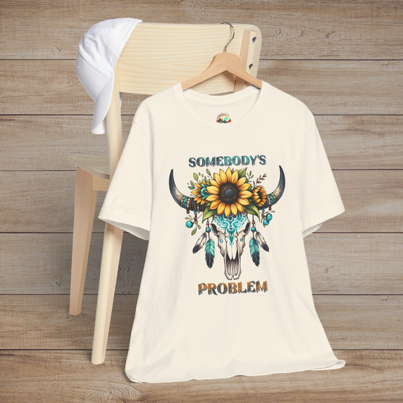 Somebody’s Problem T-Shirt with a vibrant Boho skull design adorned with flowers and turquoise feathers on natural color fabric