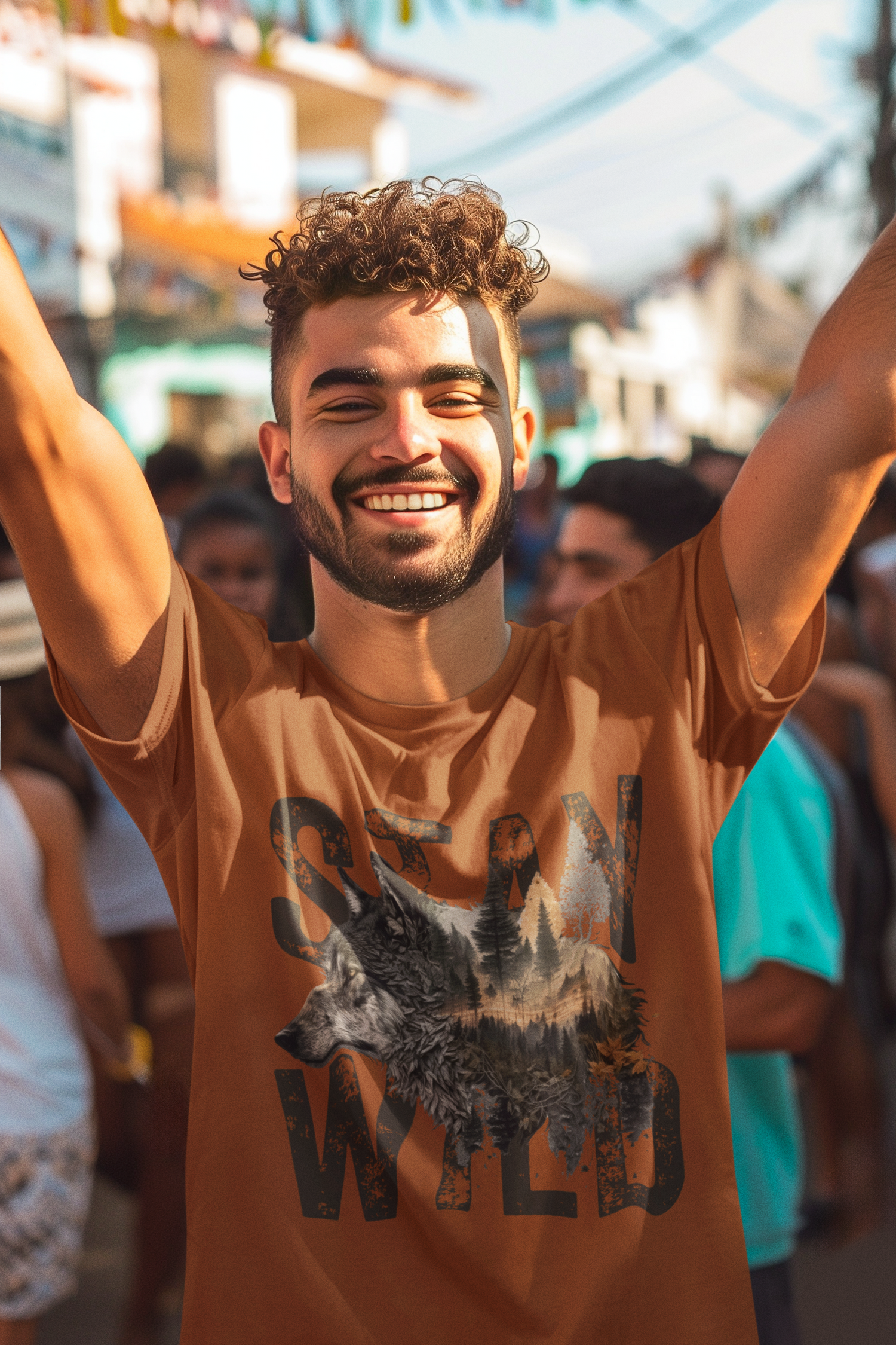 Smiling man celebrating in a crowd wearing the Stay Wild wolf t-shirt in autumn orange