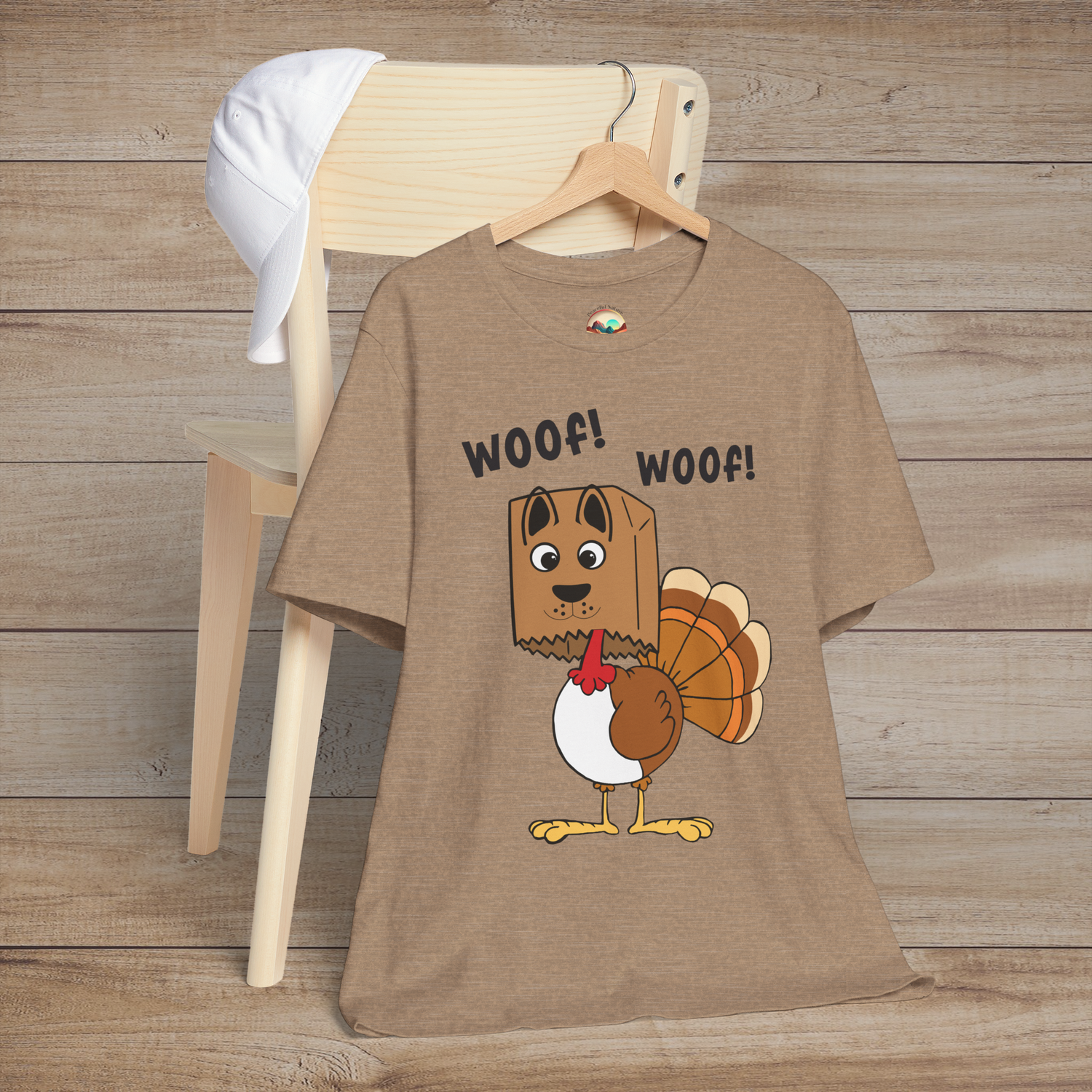Cartoon turkey pretending to be a dog with “Woof! Woof!” text on heather tan holiday tee