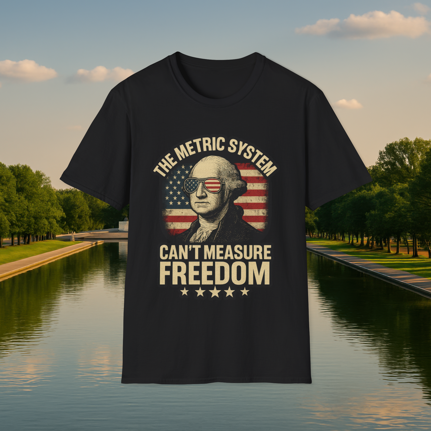 Flat lay of a black T-shirt featuring a vintage 'The Metric System Can’t Measure Freedom' George Washington design with American flag sunglasses