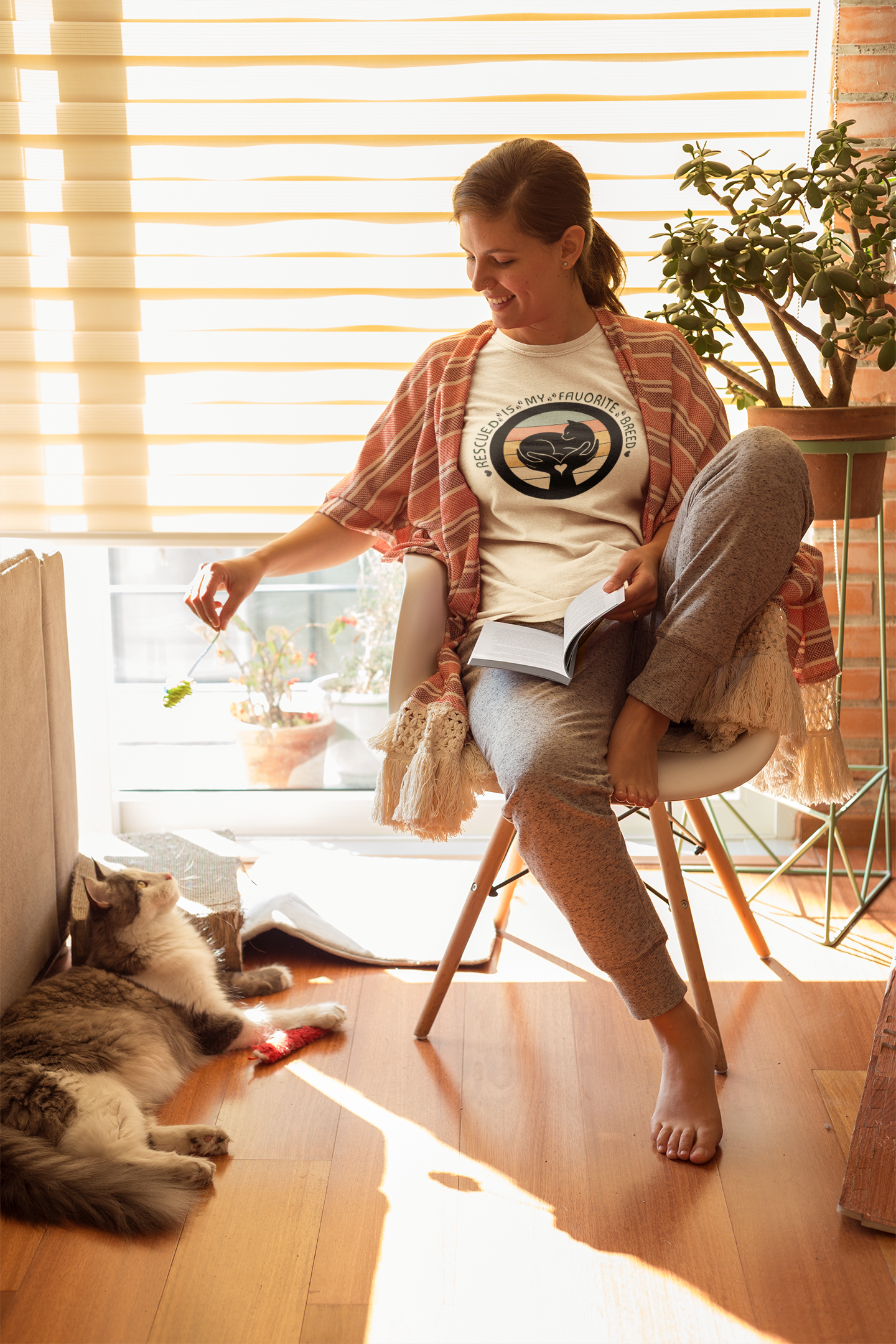 Woman sitting on a chair with a cat on the floor in a bright room.