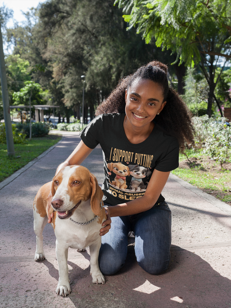 Woman kneeling on a path with a dog, wearing a t-shirt with a graphic design.